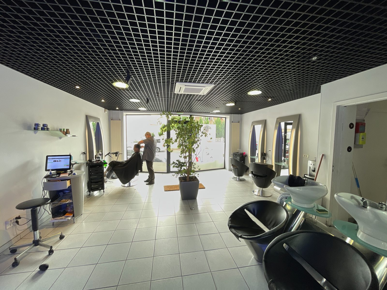 Salon homme : coupe en cours près de la grande baie vitrée